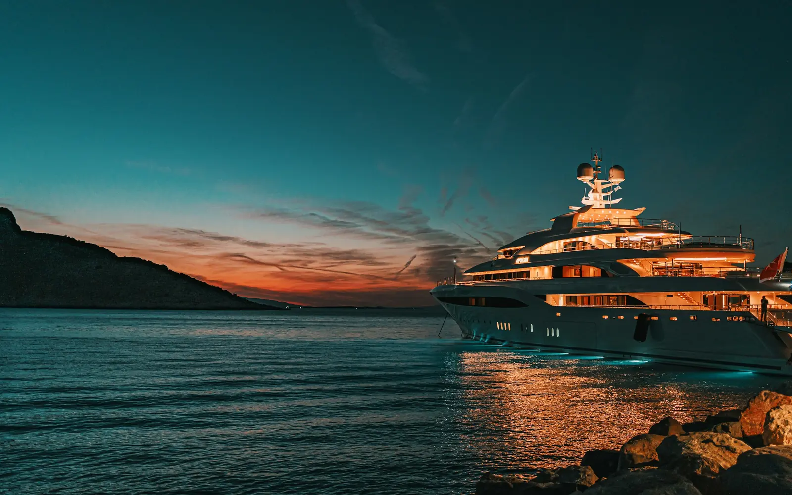 A superyacht at anchor under a copper sunset