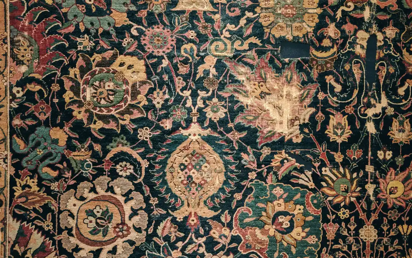 An antique midnight green carpet woven with gold and rose florals